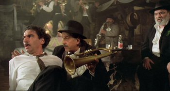 Movie still from “Underground” (1995), directed by Emir Kusturica – A man in a hat is holding a trumpet; Medium shot, Low angle