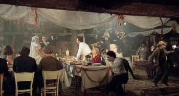 Movie still from “Underground” (1995), directed by Emir Kusturica – A group of people sitting at a table in a restaurant; Wide shot, High angle