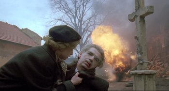 Movie still from “Underground” (1995), directed by Emir Kusturica – A man and a woman in front of a burning building; Medium shot, Low angle