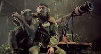 Movie still from “Underground” (1995), directed by Emir Kusturica – A man sitting next to a monkey holding a gun; Medium shot, Low angle
