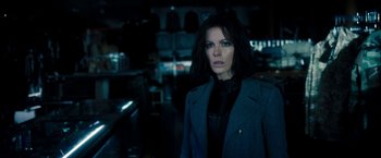 Movie still from “Underworld: Awakening” (2012), directed by Björn Stein – A woman standing in a dark room wearing a jacket; Medium shot, Over the shoulder angle