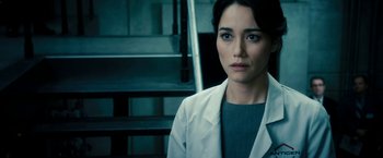 Movie still from “Underworld: Awakening” (2012), directed by Björn Stein – A woman in a lab coat standing in front of stairs; Close Up shot, Over the shoulder angle