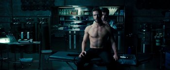 Movie still from “Underworld: Awakening” (2012), directed by Björn Stein – A man sitting on top of a table next to another man; Medium shot, Over the shoulder angle