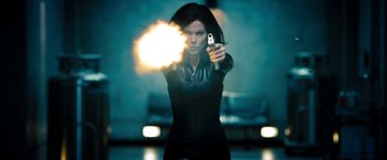 Movie still from “Underworld: Awakening” (2012), directed by Björn Stein – A woman is holding a gun and aiming it at the camera; Medium shot, Low angle