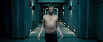 Movie still from “Underworld: Awakening” (2012), directed by Björn Stein – A man standing in a hallway with no shirt on; Medium shot, Low angle