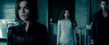 Movie still from “Underworld: Awakening” (2012), directed by Björn Stein – A woman in a white dress standing next to a door; Medium shot, Over the shoulder angle