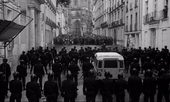 Movie still from “A Room in Town” (1982), directed by Jacques Demy – A black and white photo of a crowd of people in the street; Extreme Wide shot, High angle