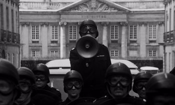 Movie still from “A Room in Town” (1982), directed by Jacques Demy – A group of people in helmets and goggles; Medium shot, Low angle