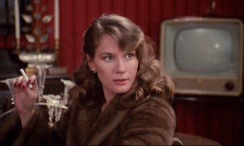 Movie still from “A Room in Town” (1982), directed by Jacques Demy – A woman wearing a fur coat sitting in a chair; Close Up shot, Over the shoulder angle