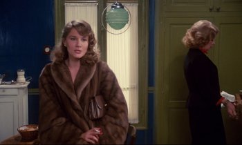 Movie still from “A Room in Town” (1982), directed by Jacques Demy – A woman wearing a fur coat in front of a window; Medium shot, Over the shoulder angle