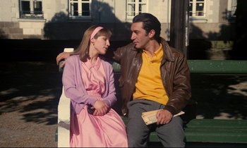 Movie still from “A Room in Town” (1982), directed by Jacques Demy – A man and a woman sitting on a park bench; Medium shot, High angle