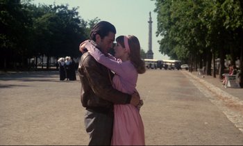 Movie still from “A Room in Town” (1982), directed by Jacques Demy – A man and a woman embracing on a street; Medium shot, Low angle
