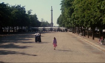 Movie still from “A Room in Town” (1982), directed by Jacques Demy – A little girl in a pink dress walking down the street; Extreme Wide shot, High angle