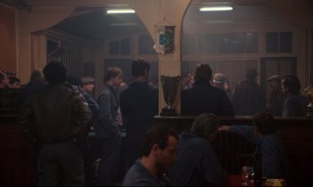 Movie still from “A Room in Town” (1982), directed by Jacques Demy – A group of people standing in a room; Wide shot, Over the shoulder angle
