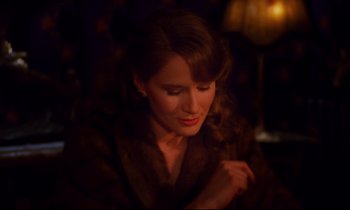 Movie still from “A Room in Town” (1982), directed by Jacques Demy – A beautiful woman sitting down in a dark room; Close Up shot, Over the shoulder angle