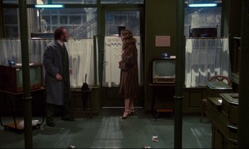 Movie still from “A Room in Town” (1982), directed by Jacques Demy – A woman in a brown coat standing next to a man in a brown coat; Wide shot, High angle