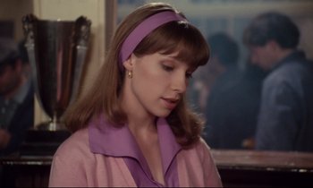 Movie still from “A Room in Town” (1982), directed by Jacques Demy – A young woman wearing a pink shirt and a purple headband; Close Up shot, Over the shoulder angle