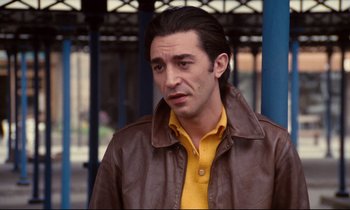 Movie still from “A Room in Town” (1982), directed by Jacques Demy – A man wearing a brown jacket and a yellow shirt; Close Up shot, Low angle