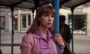 Movie still from “A Room in Town” (1982), directed by Jacques Demy – A woman in a pink shirt and purple jacket; Close Up shot, Low angle