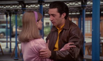 Movie still from “A Room in Town” (1982), directed by Jacques Demy – A man and a girl are standing together; Medium shot, Over the shoulder angle