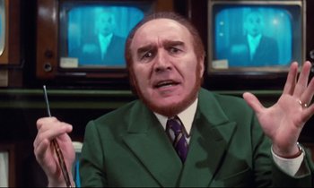 Movie still from “A Room in Town” (1982), directed by Jacques Demy – An older man wearing a green suit and a purple tie; Close Up shot, Low angle