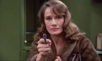 Movie still from “A Room in Town” (1982), directed by Jacques Demy – A woman in a fur coat holding a gun in her hand; Close Up shot, High angle