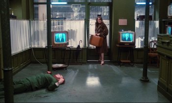 Movie still from “A Room in Town” (1982), directed by Jacques Demy – A man lying on the ground next to a woman holding a briefcase; Wide shot, High angle
