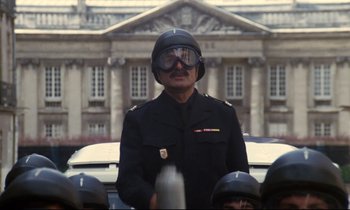 Movie still from “A Room in Town” (1982), directed by Jacques Demy – A man in a black uniform with a helmet on; Medium shot, Low angle