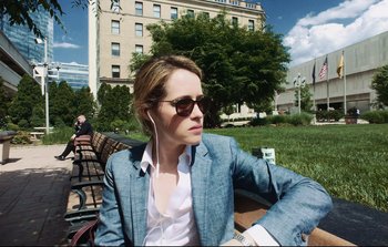 Movie still from “Unsane” (2018), directed by Steven Soderbergh – A woman sitting on top of a park bench wearing sunglasses; Medium shot, Low angle