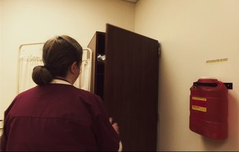 Movie still from “Unsane” (2018), directed by Steven Soderbergh – A woman standing in front of an open cabinet door; Medium shot, Over the shoulder angle