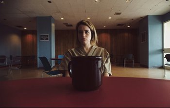 Movie still from “Unsane” (2018), directed by Steven Soderbergh – A woman sitting at a table with a large bowl in front of her face; Close Up shot, Low angle