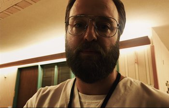 Movie still from “Unsane” (2018), directed by Steven Soderbergh – A person with a beard wearing glasses; Close Up shot, Low angle