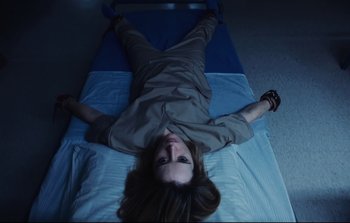 Movie still from “Unsane” (2018), directed by Steven Soderbergh – A woman laying on top of a bed in a room; Medium shot, Overhead angle