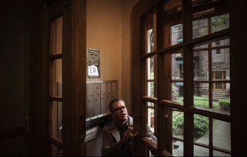 Movie still from “Unsane” (2018), directed by Steven Soderbergh – A man sitting in front of a window with a phone; Medium shot, Low angle