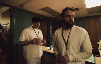 Movie still from “Unsane” (2018), directed by Steven Soderbergh – A couple of men standing next to each other in a room; Medium shot, Low angle