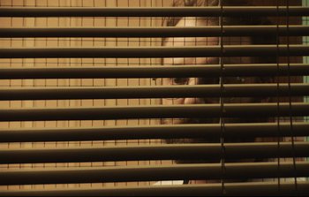 Movie still from “Unsane” (2018), directed by Steven Soderbergh – A person looking out of a window through blinds; Extreme Close Up shot, Low angle