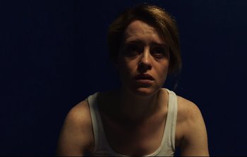 Movie still from “Unsane” (2018), directed by Steven Soderbergh – A young woman is sitting in a dark room; Close Up shot, Over the shoulder angle