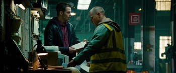 Movie still from “Unstoppable” (2010), directed by Tony Scott – A man in a yellow vest is handing something to another man in a yellow vest; Medium shot, Over the shoulder angle