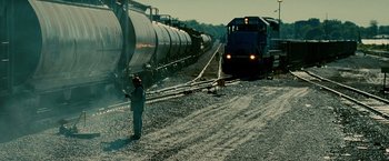 Movie still from “Unstoppable” (2010), directed by Tony Scott – A man standing next to train tracks next to train cars; Extreme Wide shot, Low angle