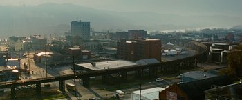 Movie still from “Unstoppable” (2010), directed by Tony Scott – An aerial view of a city with buildings and cars parked on the street; Extreme Wide shot, High angle