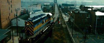 Movie still from “Unstoppable” (2010), directed by Tony Scott – A train traveling down train tracks next to buildings; Extreme Wide shot, High angle