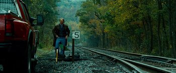 Movie still from “Unstoppable” (2010), directed by Tony Scott – A man standing next to a number sign on a train track; Wide shot, Low angle