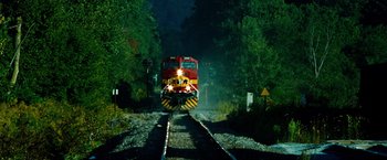 Movie still from “Unstoppable” (2010), directed by Tony Scott – A train traveling down train tracks next to a forest; Extreme Wide shot, Low angle