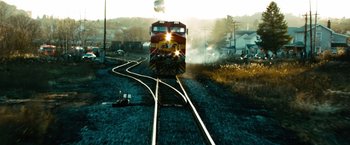Movie still from “Unstoppable” (2010), directed by Tony Scott – A train traveling down train tracks next to a small town; Extreme Wide shot, Low angle