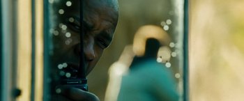 Movie still from “Unstoppable” (2010), directed by Tony Scott – A bald man with a beard is holding a cell phone in his hand; Close Up shot, Low angle