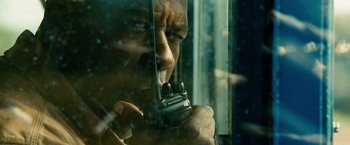 Movie still from “Unstoppable” (2010), directed by Tony Scott – A man holding a walkie talkie in front of a window; Extreme Close Up shot, Low angle