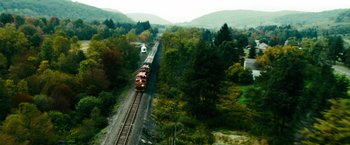 Movie still from “Unstoppable” (2010), directed by Tony Scott – A train traveling down train tracks near a forest; Extreme Wide shot, High angle