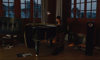 Movie still from “Until the End of the World” (1991), directed by Wim Wenders – A man sitting at a piano in a living room; Wide shot, High angle