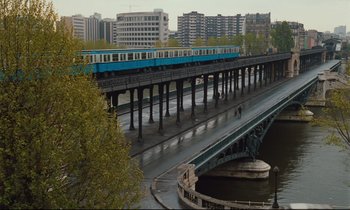 Movie still from “Until the End of the World” (1991), directed by Wim Wenders – A train traveling over a bridge over a river; Extreme Wide shot, High angle