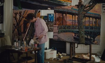 Movie still from “Until the End of the World” (1991), directed by Wim Wenders – A man standing in front of a painting in a room; Medium shot, High angle